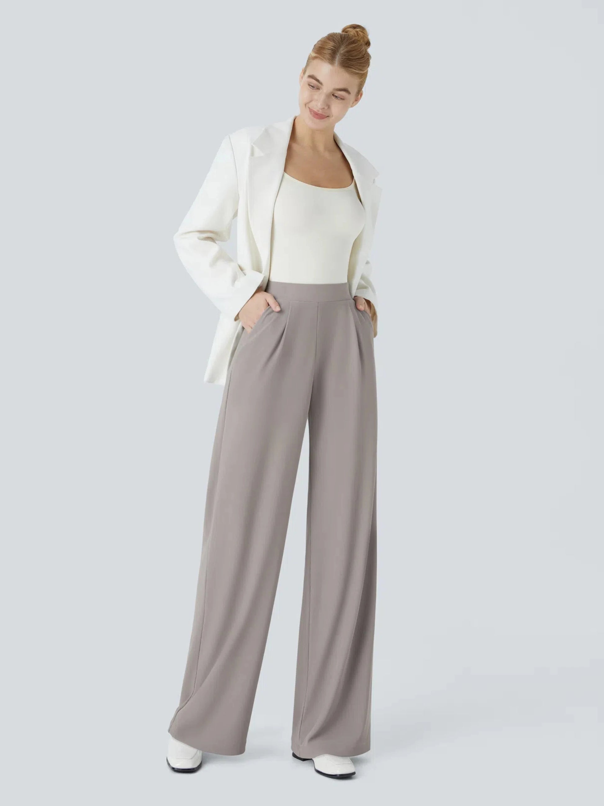 Woman wearing a white cardigan, white top, and gray wide-leg pants on a light gray background