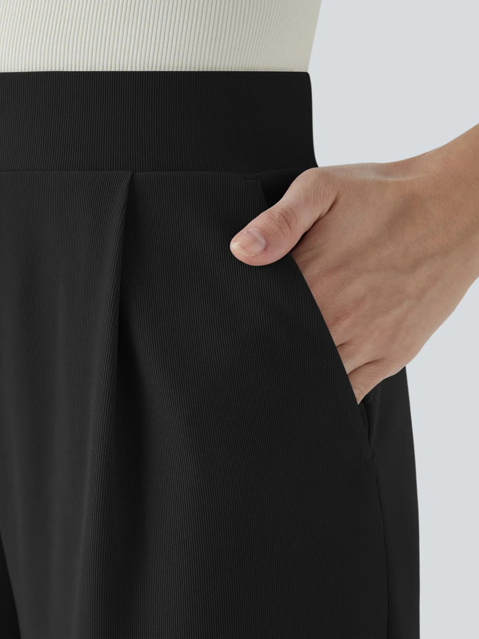 Close-up of a person wearing black pants with a neutral background
