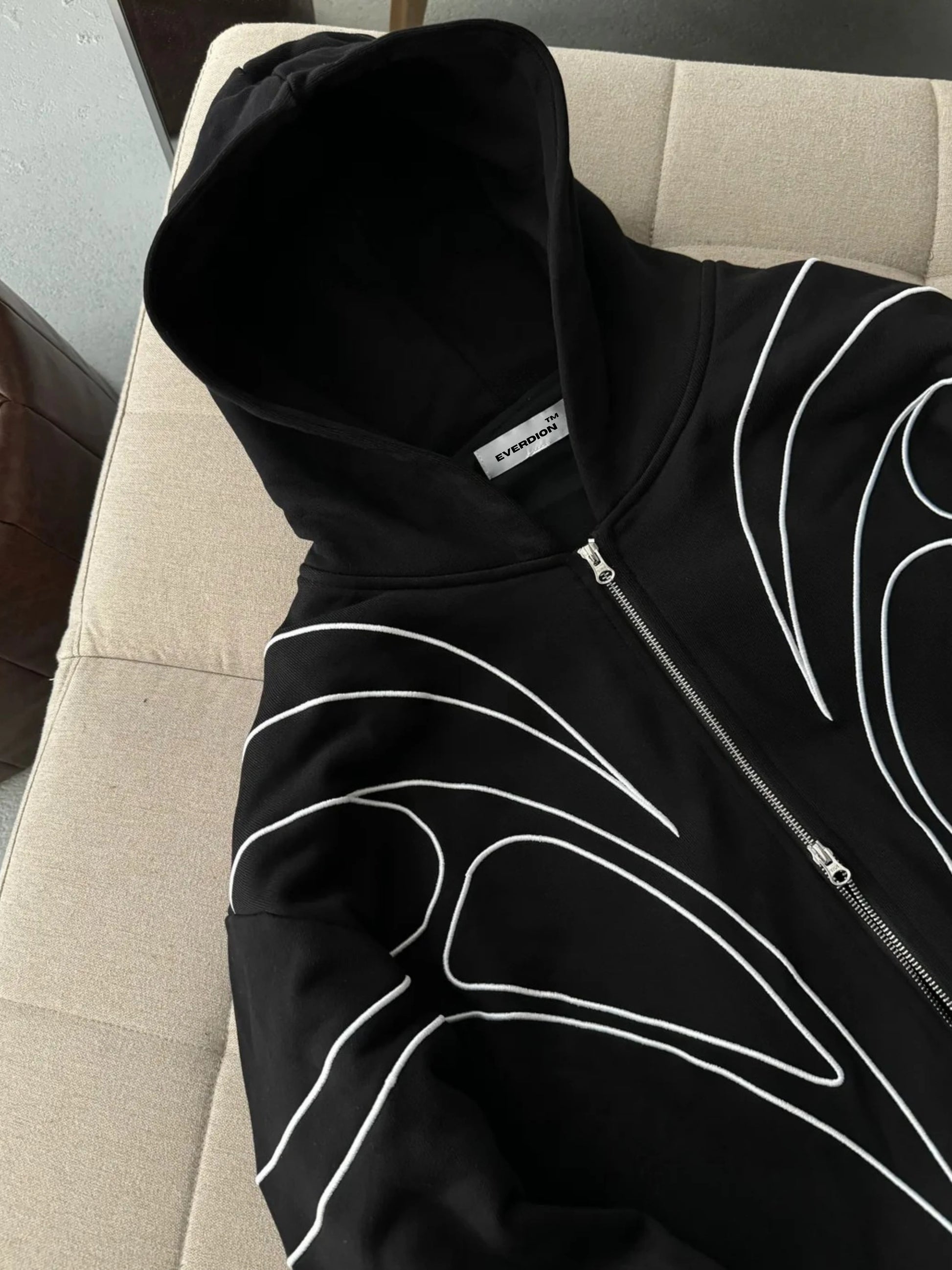 Black hoodie with white designs on a beige chair