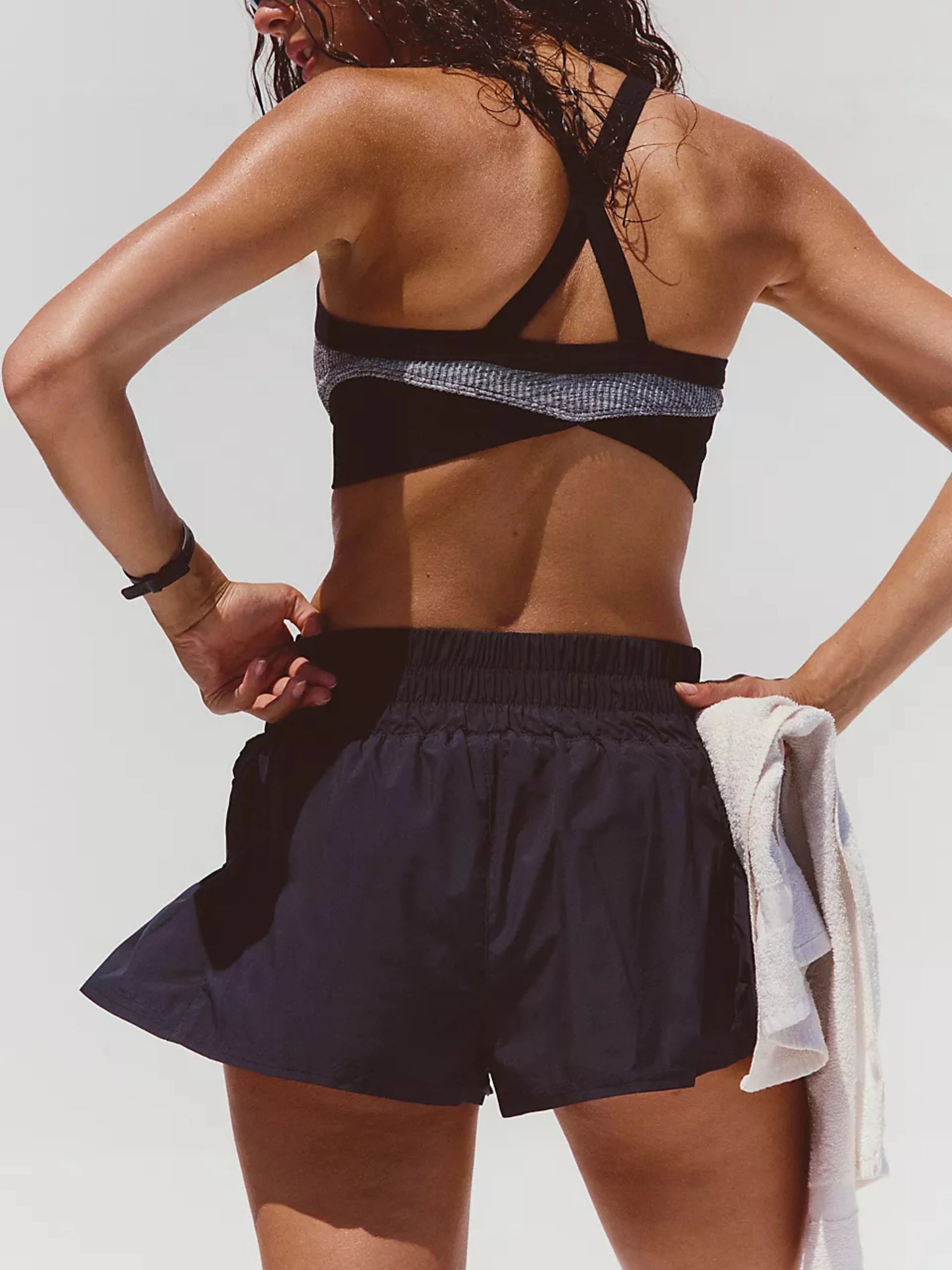 Person wearing a black sports bra and shorts with a white background