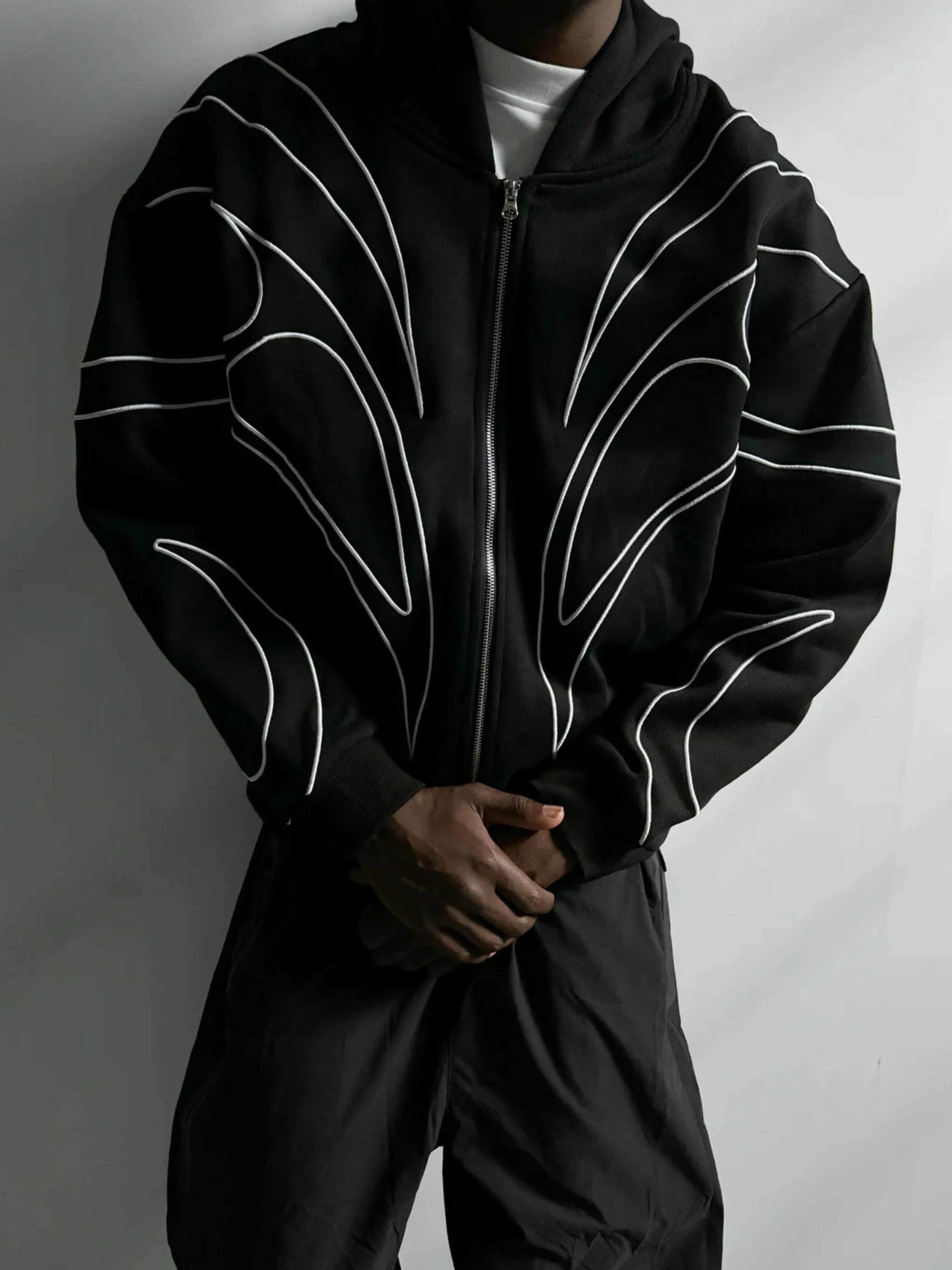 Black hoodie with white line design worn by a person on a gray background