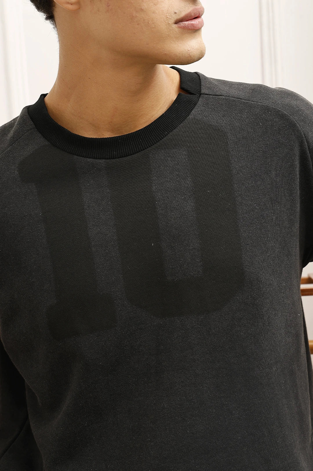 Person wearing a dark gray sweater with a blurred background