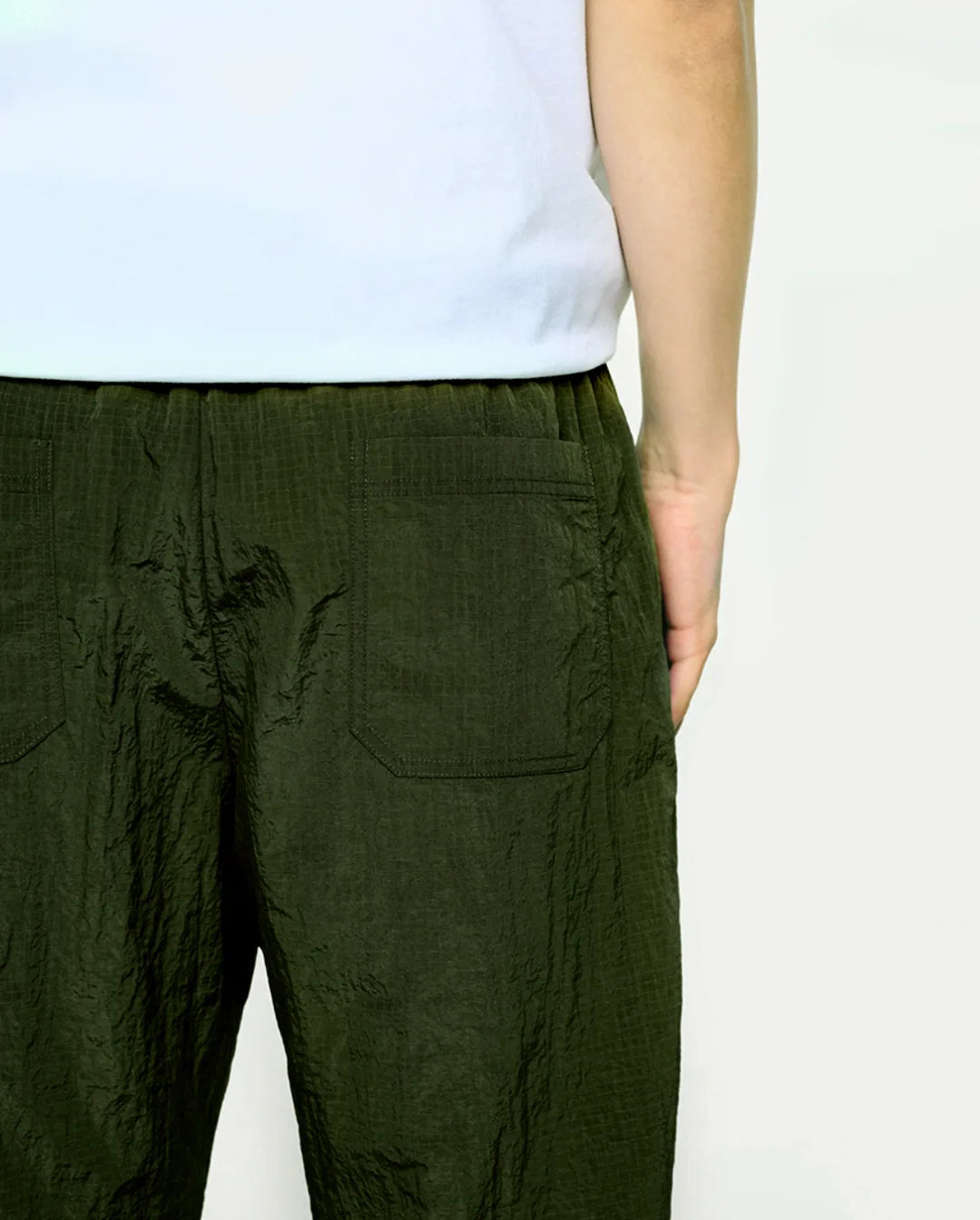 Person wearing olive pants on a plain background