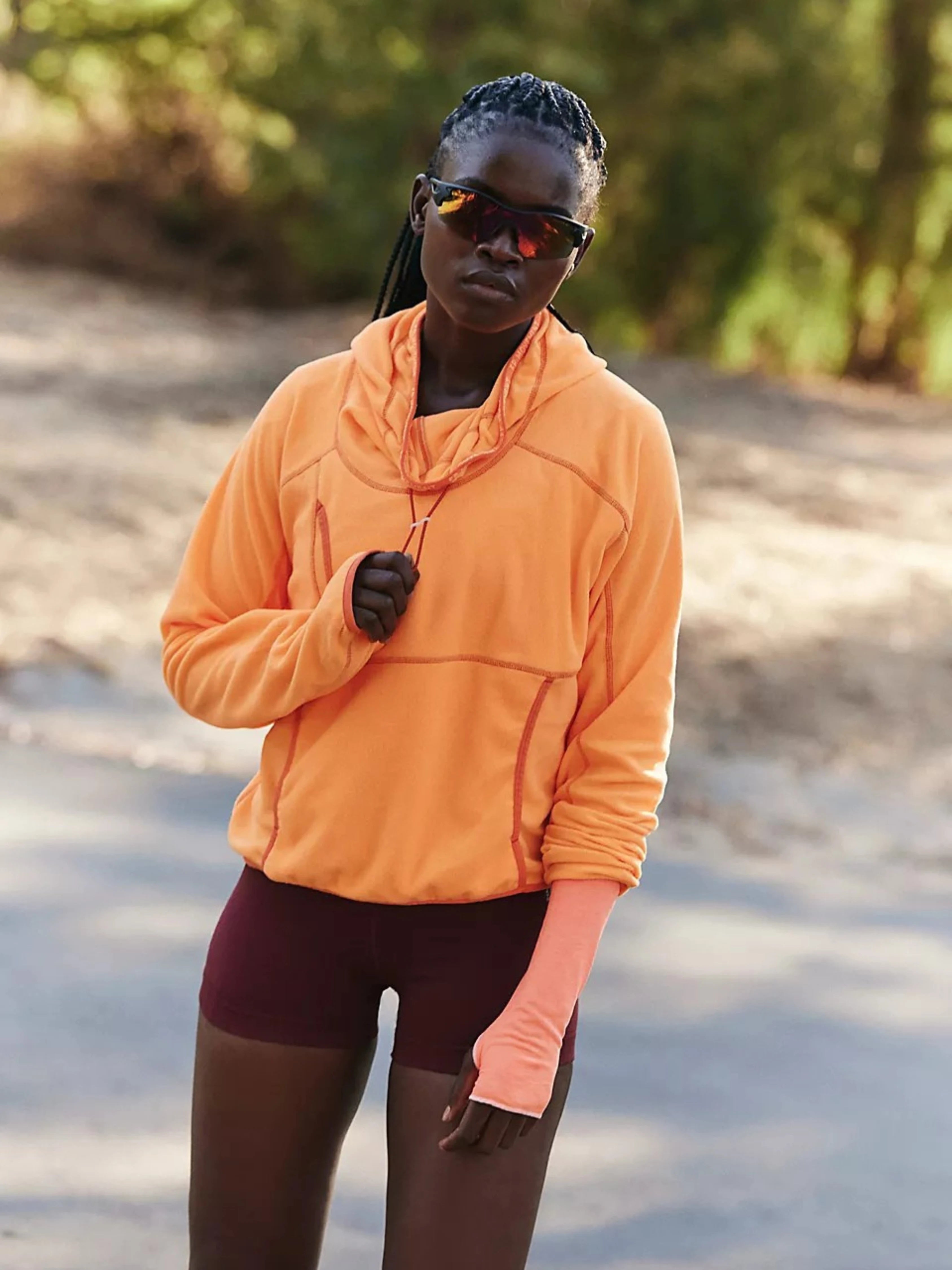 Person wearing an orange pullover and maroon shorts outdoors