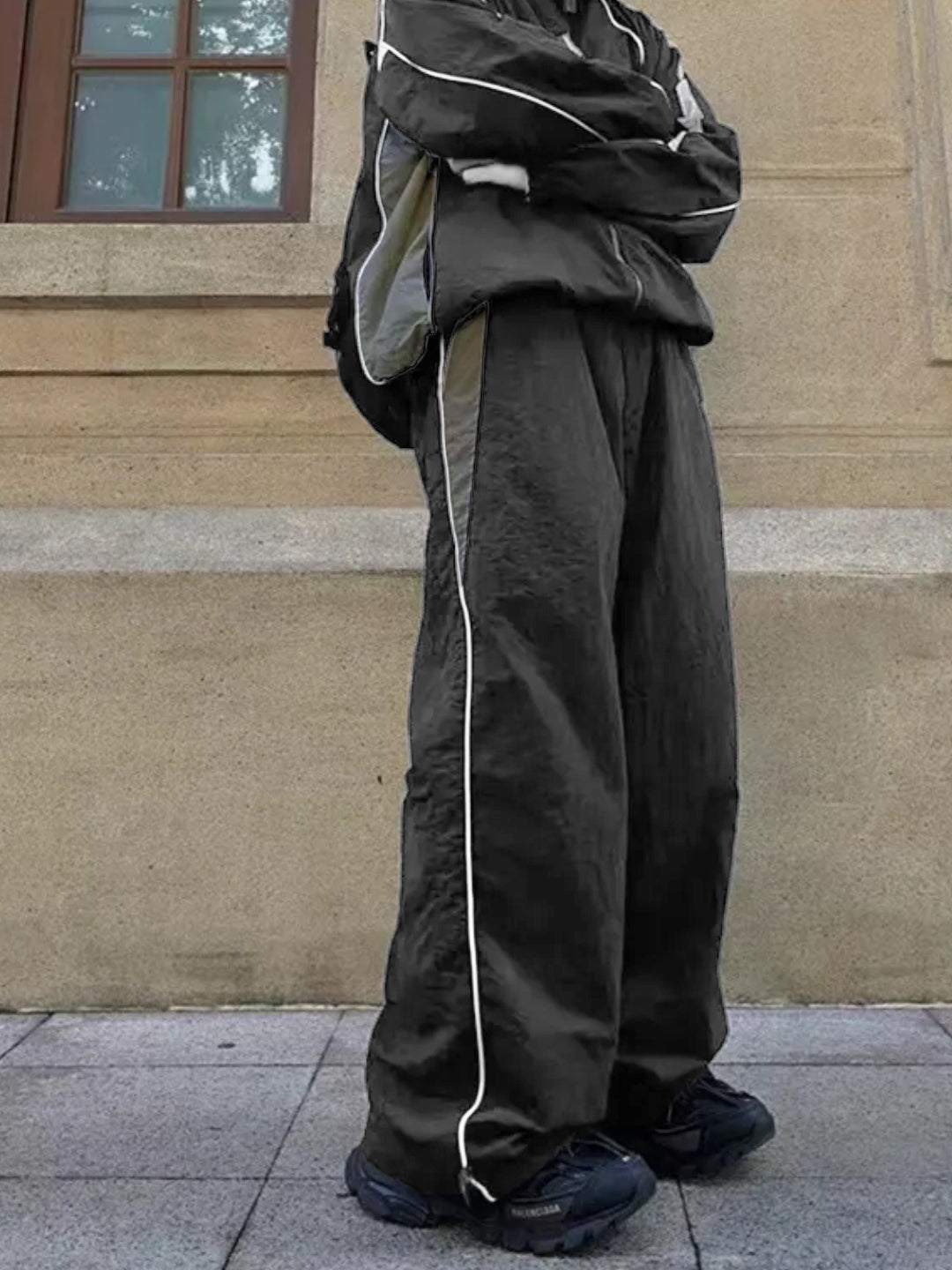 dark grey trackpants with contrast white piping and an elasticated waistband with drawstrings.
