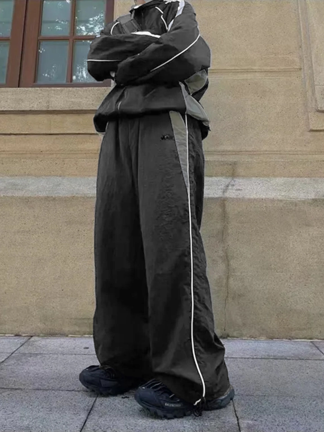 dark grey trackpants with contrast white piping and an elasticated waistband with drawstrings.