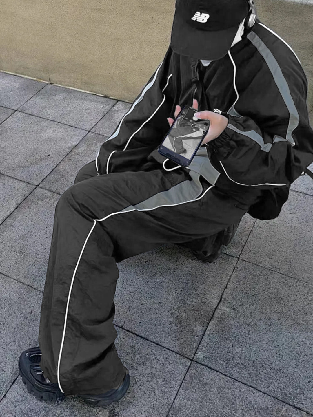 dark grey trackpants with contrast white piping and an elasticated waistband with drawstrings.