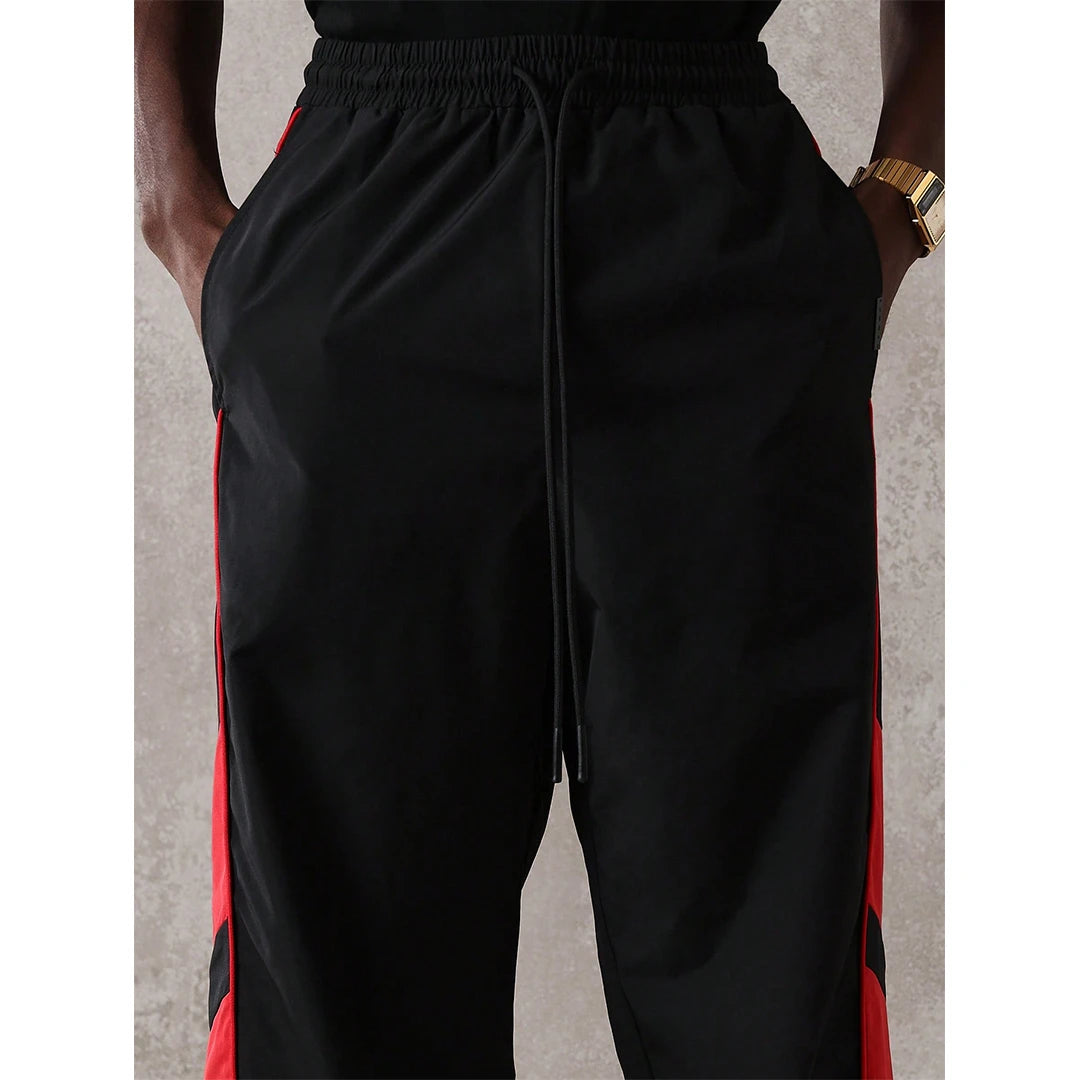 Black pants with red side stripes on a neutral background