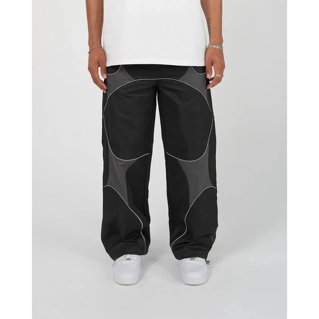 Person wearing black pants with gray accents on a white background