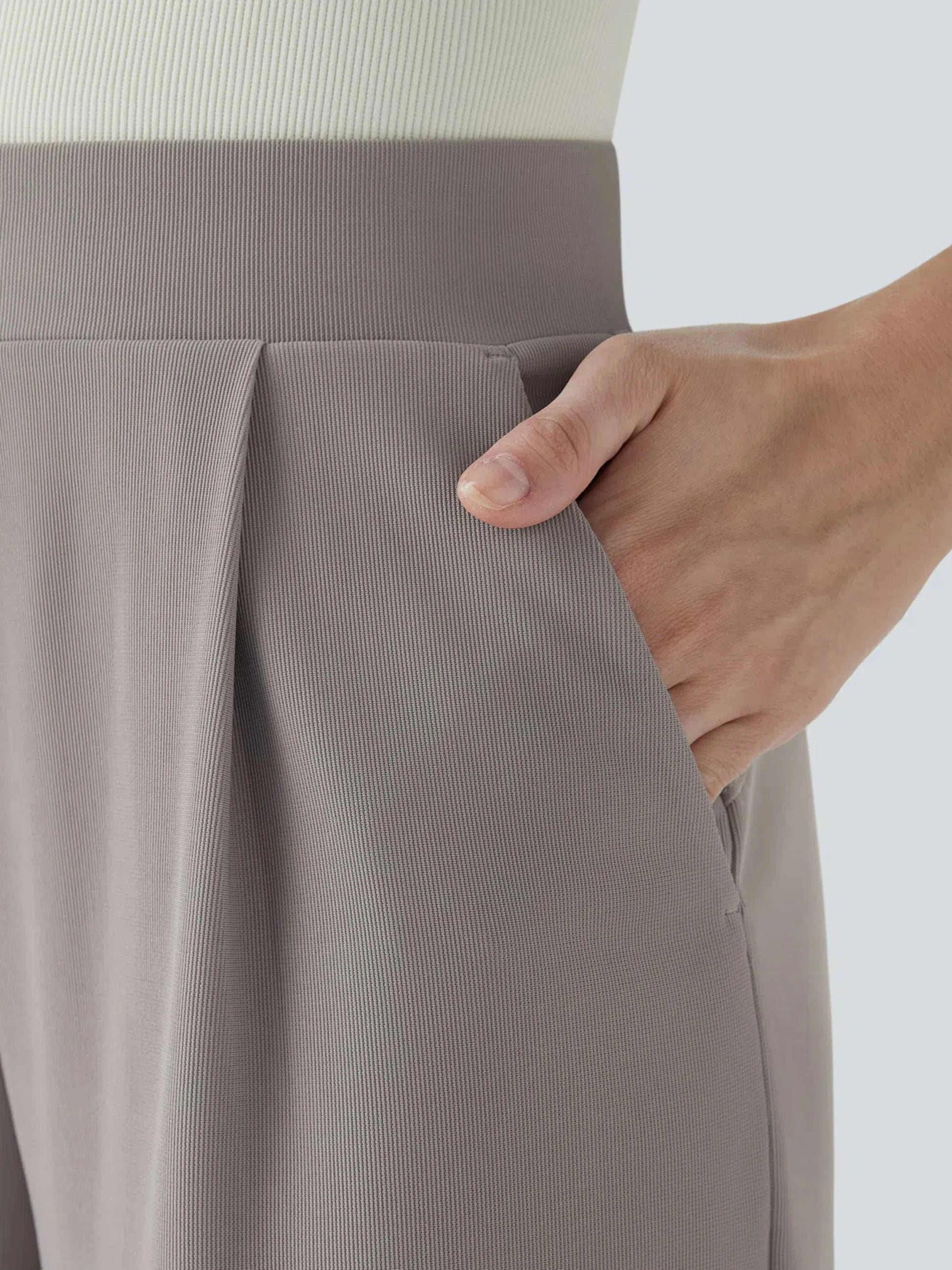 Close-up of a person wearing gray pants with a white background
