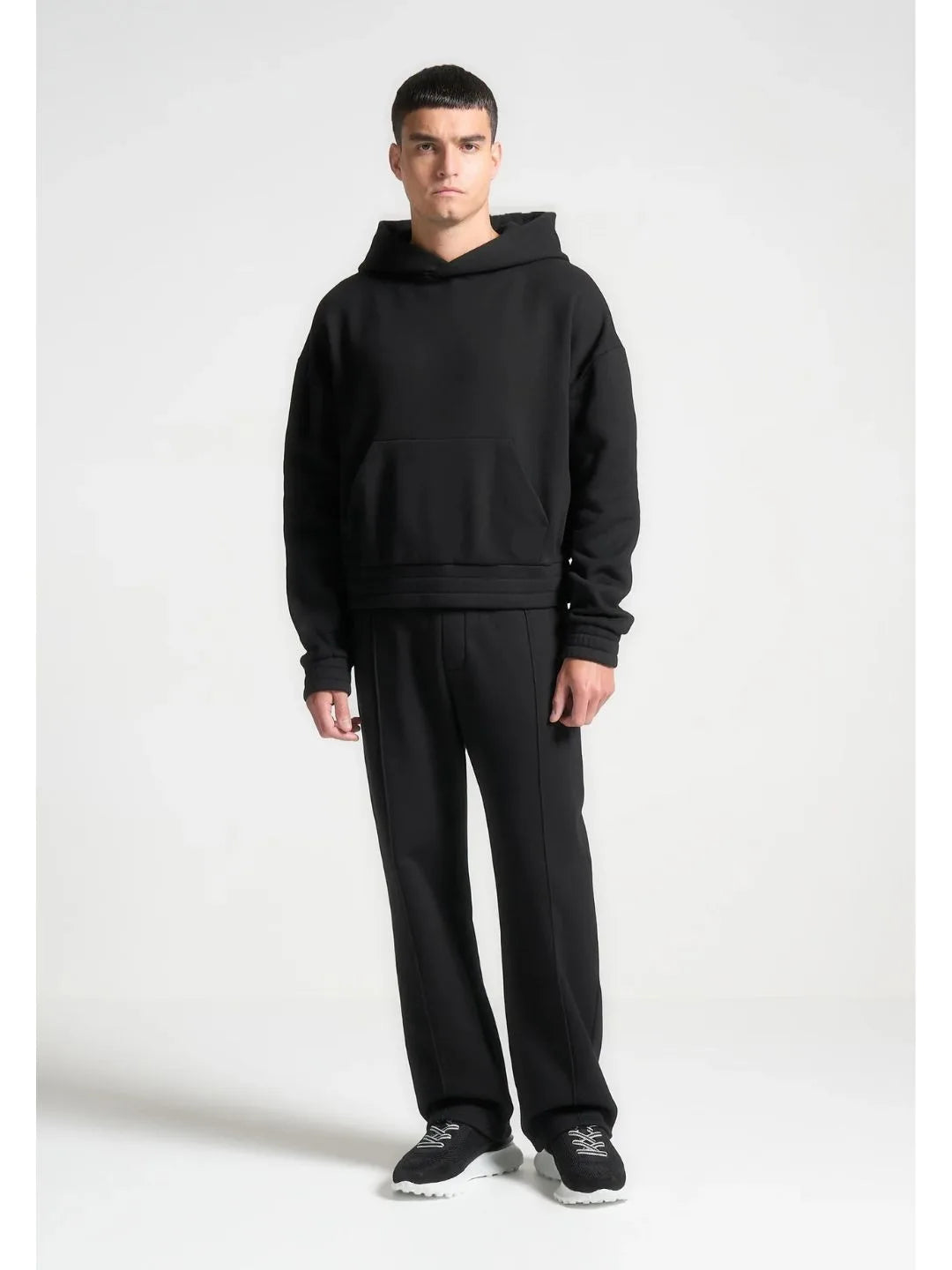 Man wearing a black hoodie and pants on a white background