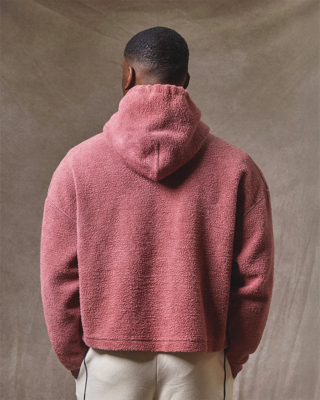 Person wearing a pink fleece jacket against a beige background