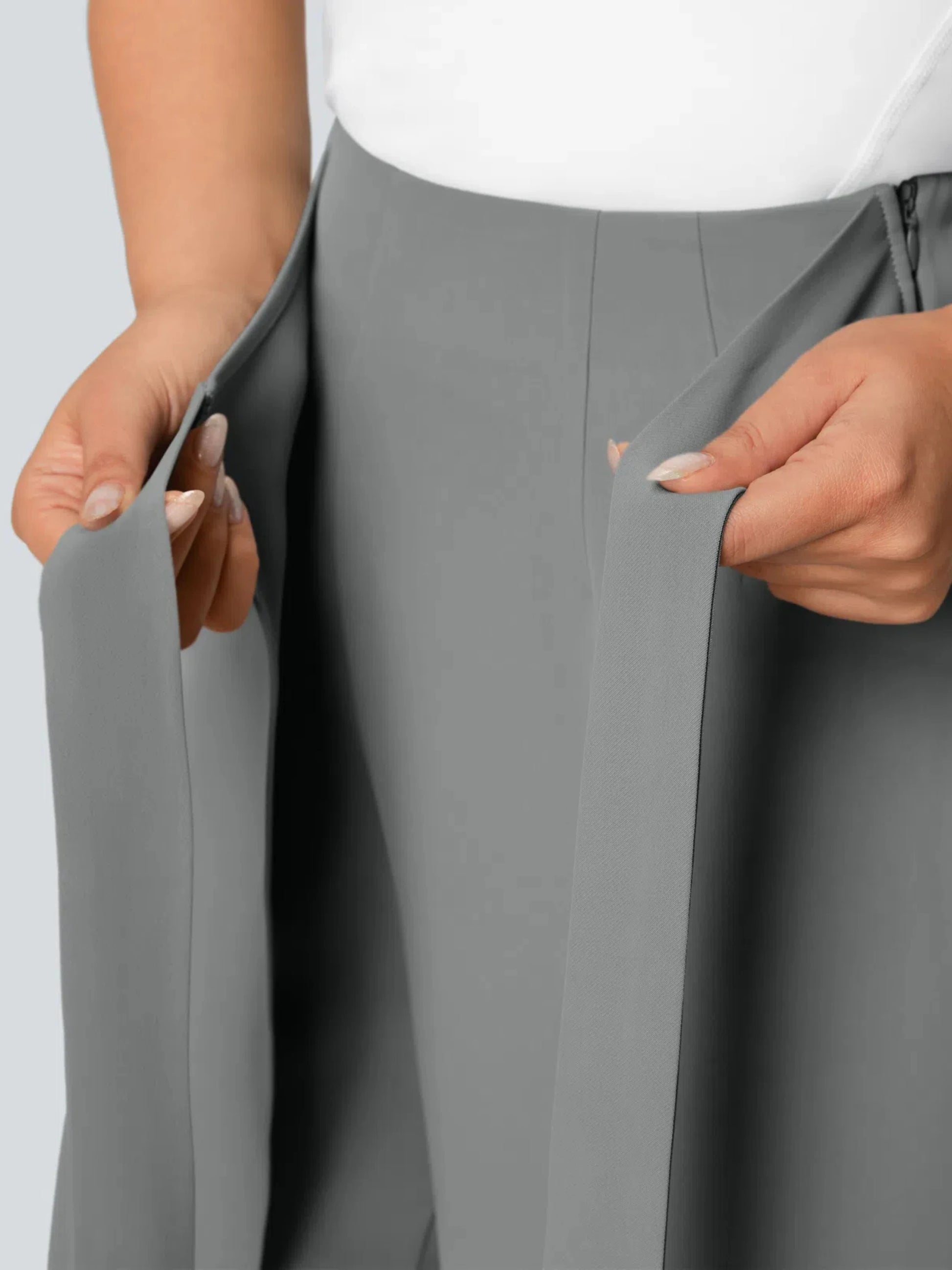 Gray pants being adjusted by a person on a light gray background