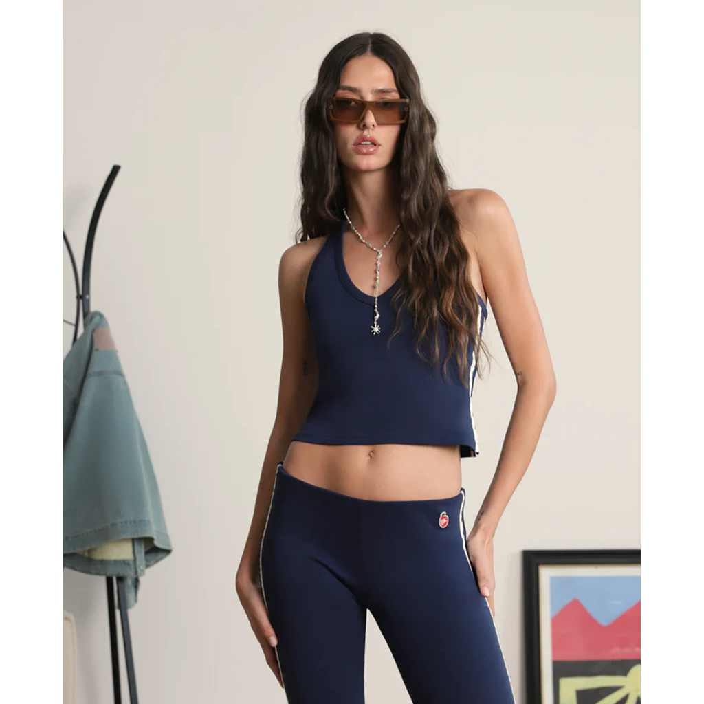 Woman wearing a navy blue sports bra and leggings with sunglasses indoors.