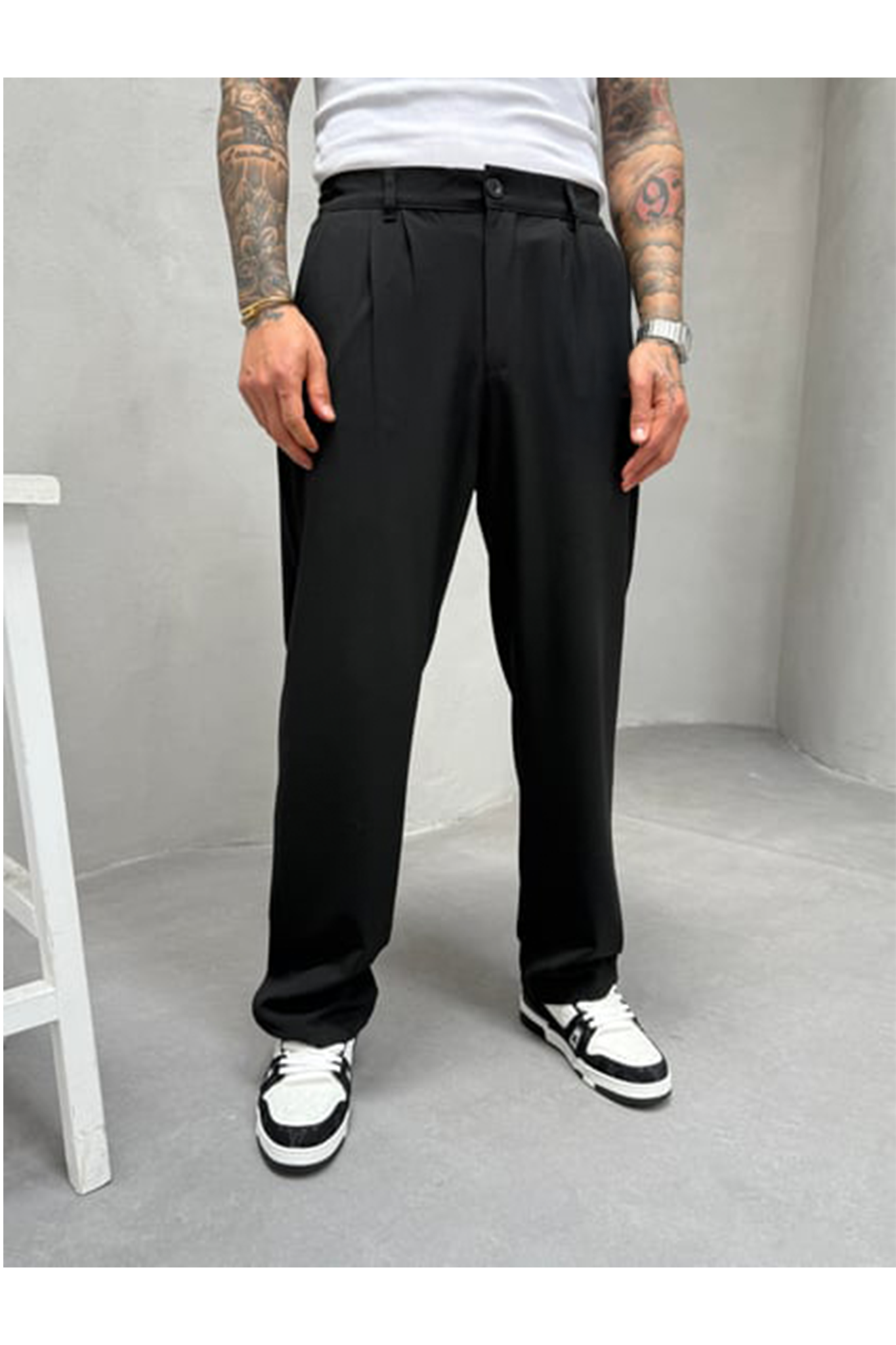 Person wearing black pants and white sneakers in a minimalistic setting