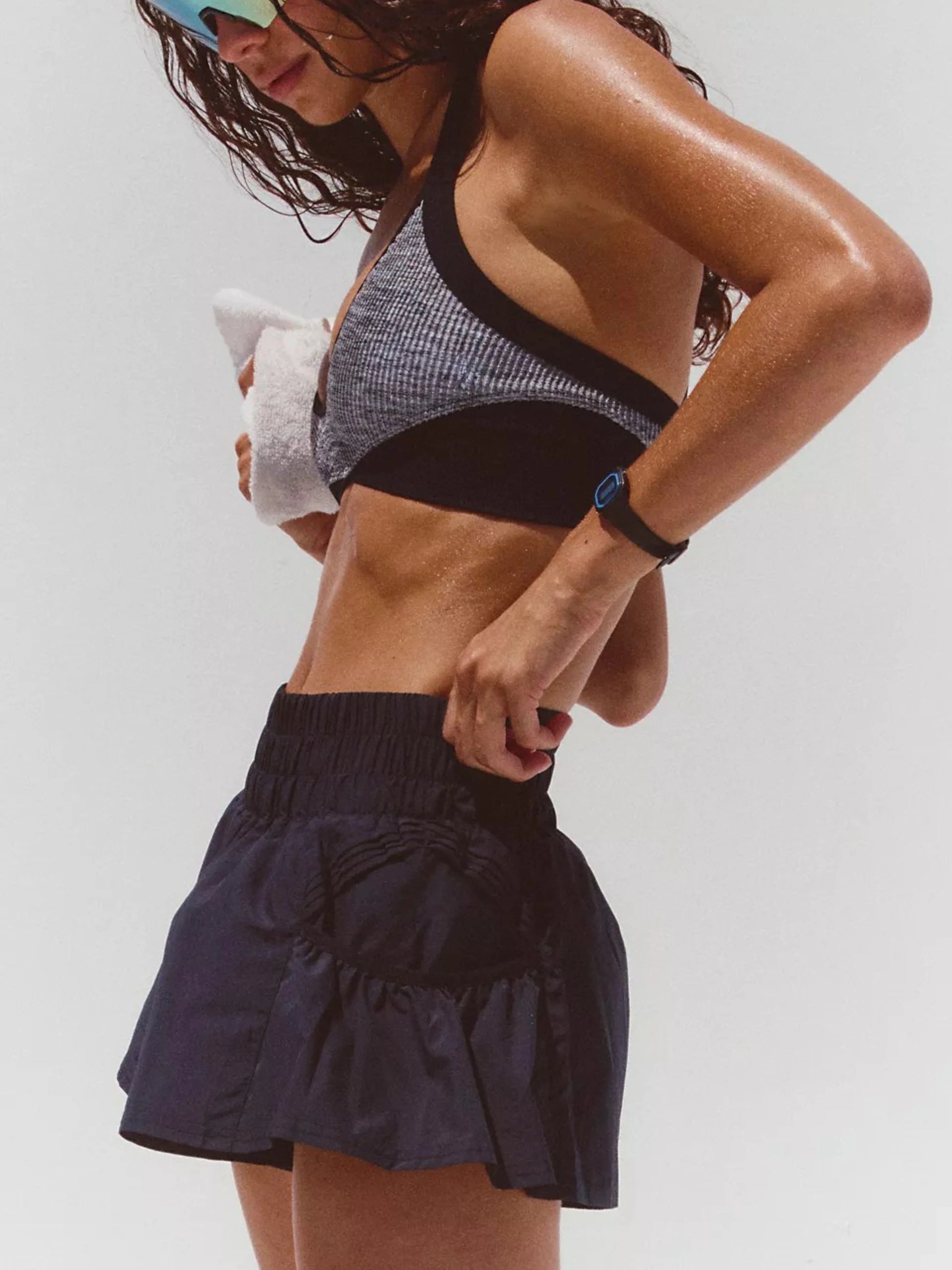 Woman wearing a black sports bra and navy blue shorts on a white background