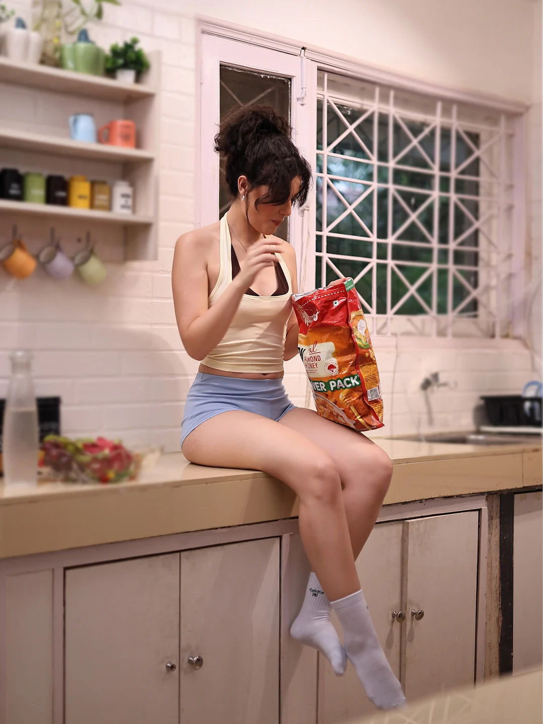 Woman sitting on a kitchen counter holding a snack bag
