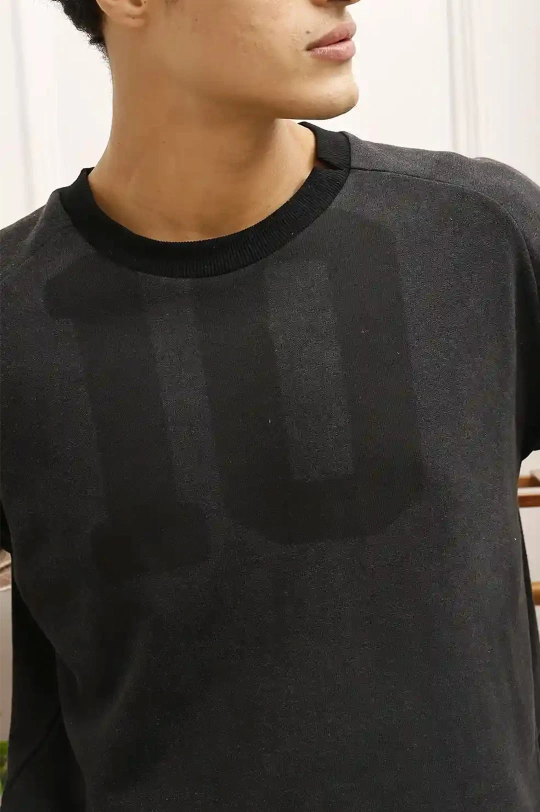 Person wearing a black t-shirt with a large dark stain on the chest.