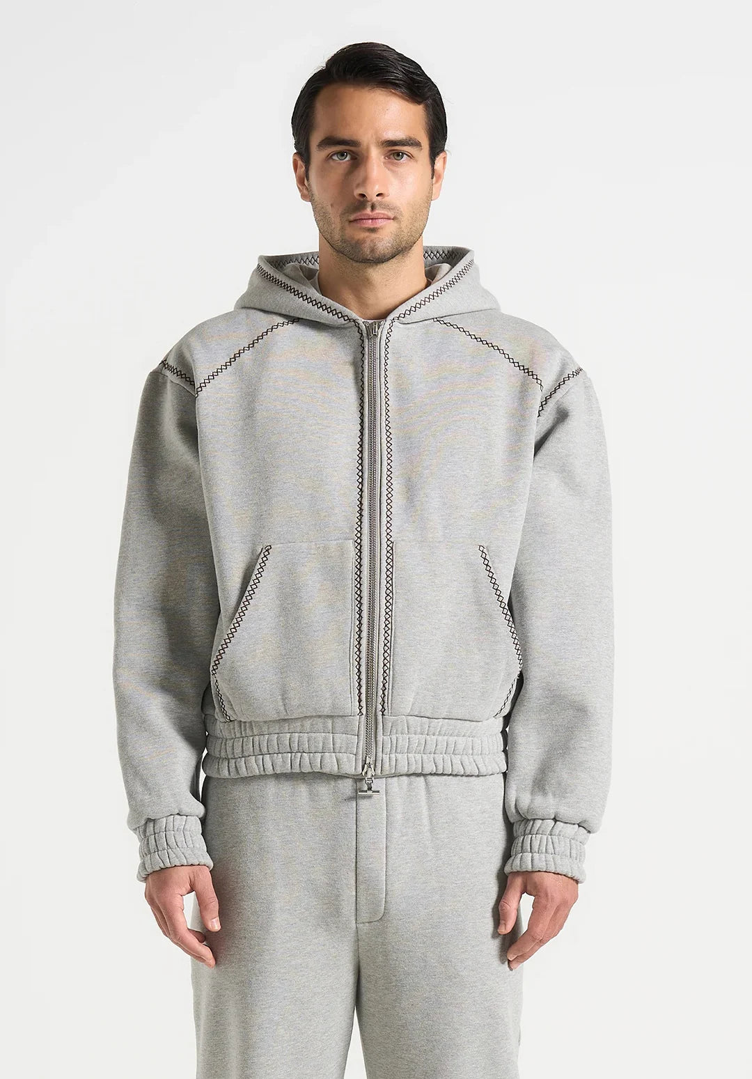 Man wearing a gray hoodie and pants on a white background