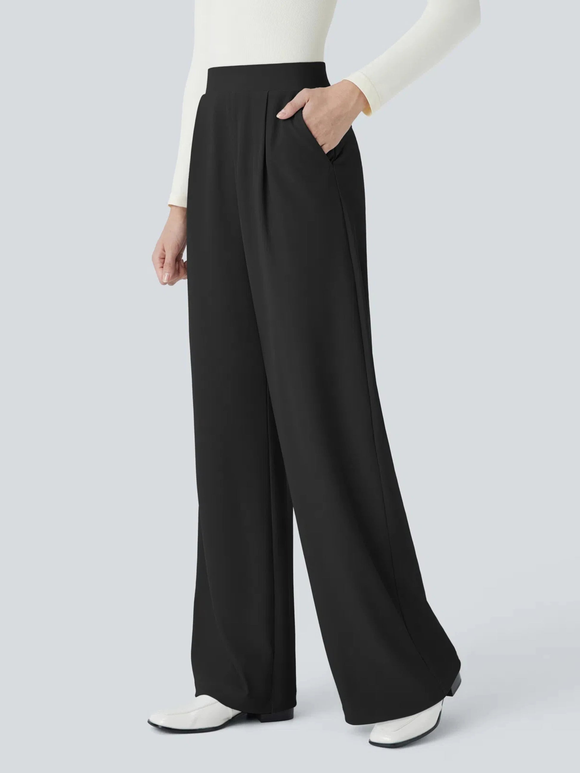 Person wearing black wide-leg pants with a white top on a light gray background