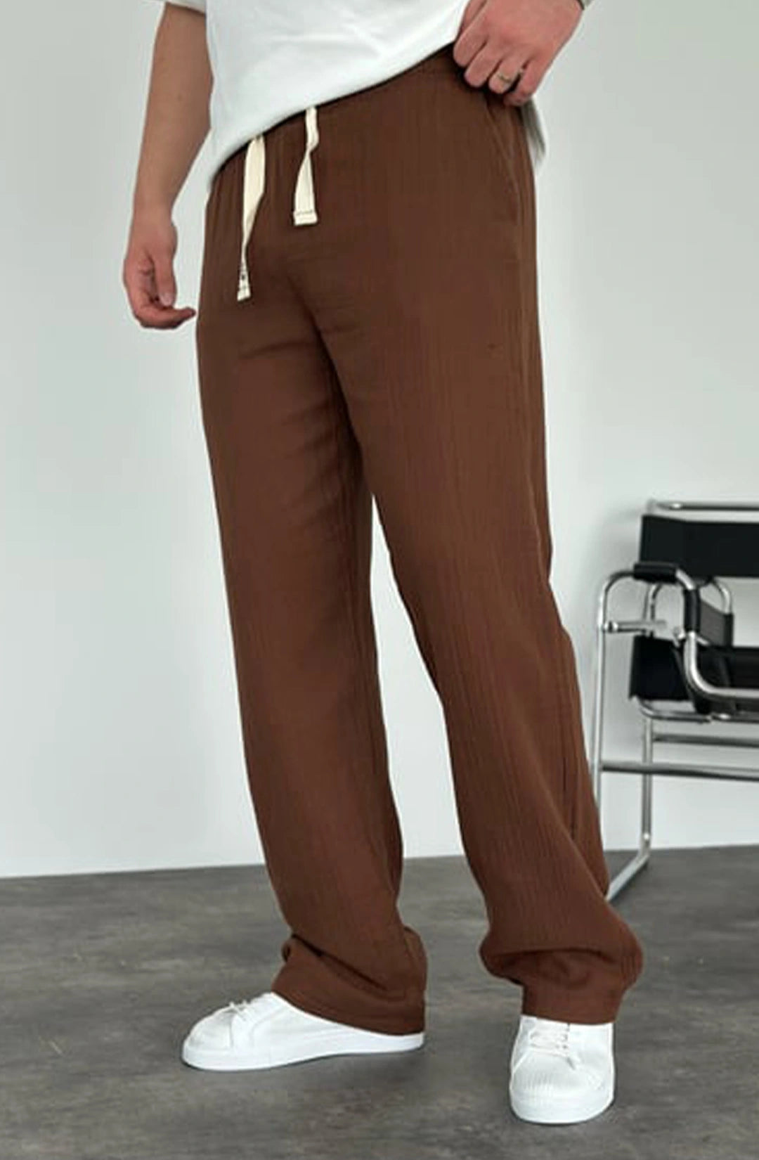 Person wearing brown pants and white shoes on a plain background