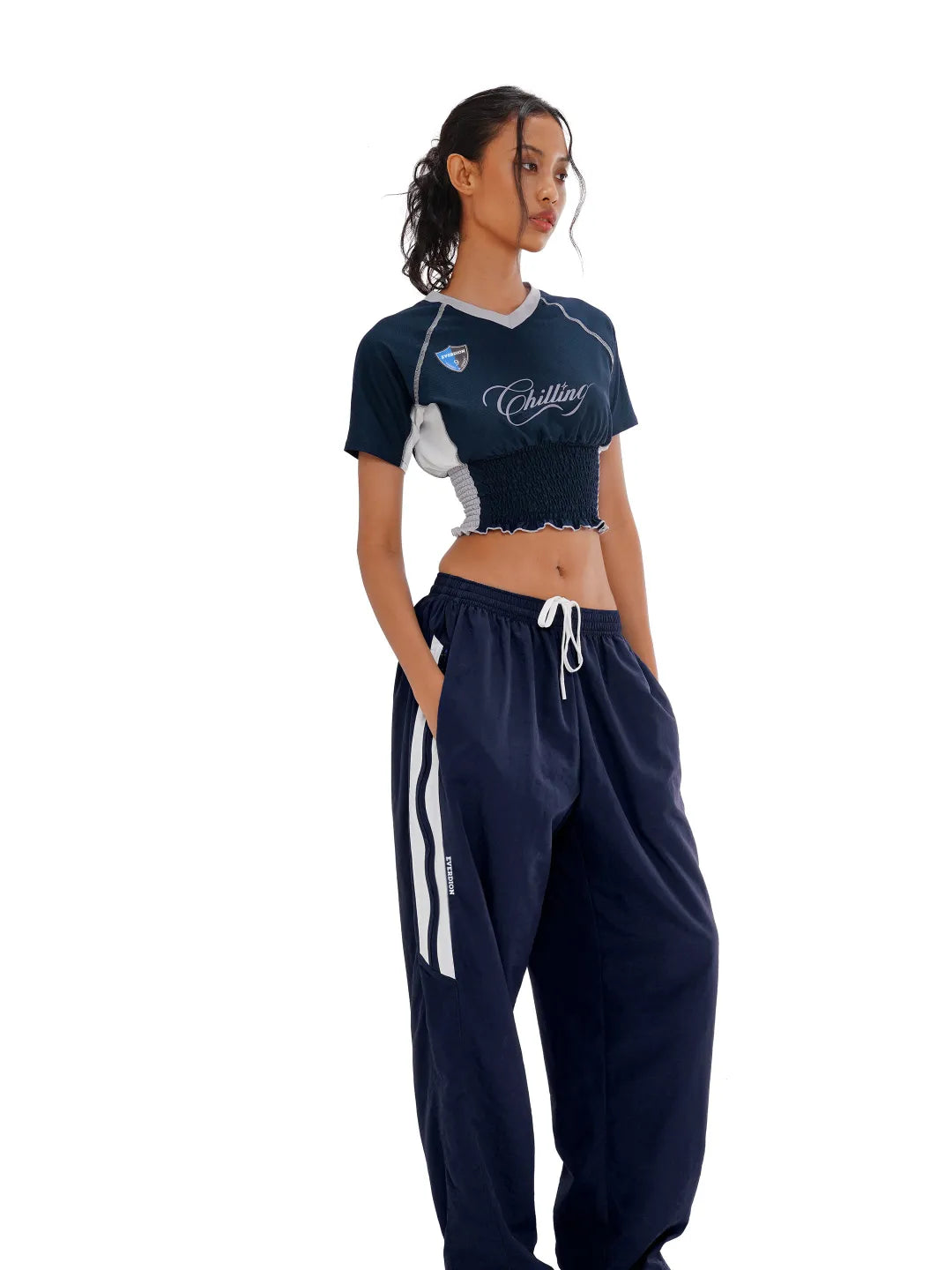 Woman wearing a navy tracksuit with white accents on a white background