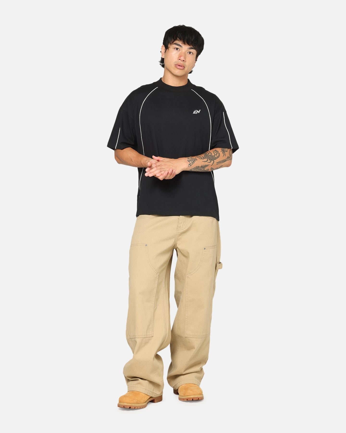 Person wearing a black t-shirt and beige pants on a white background