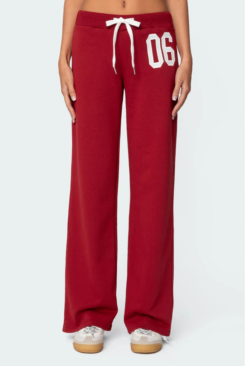 Red sweatpants with white drawstring and '06' text on a white background