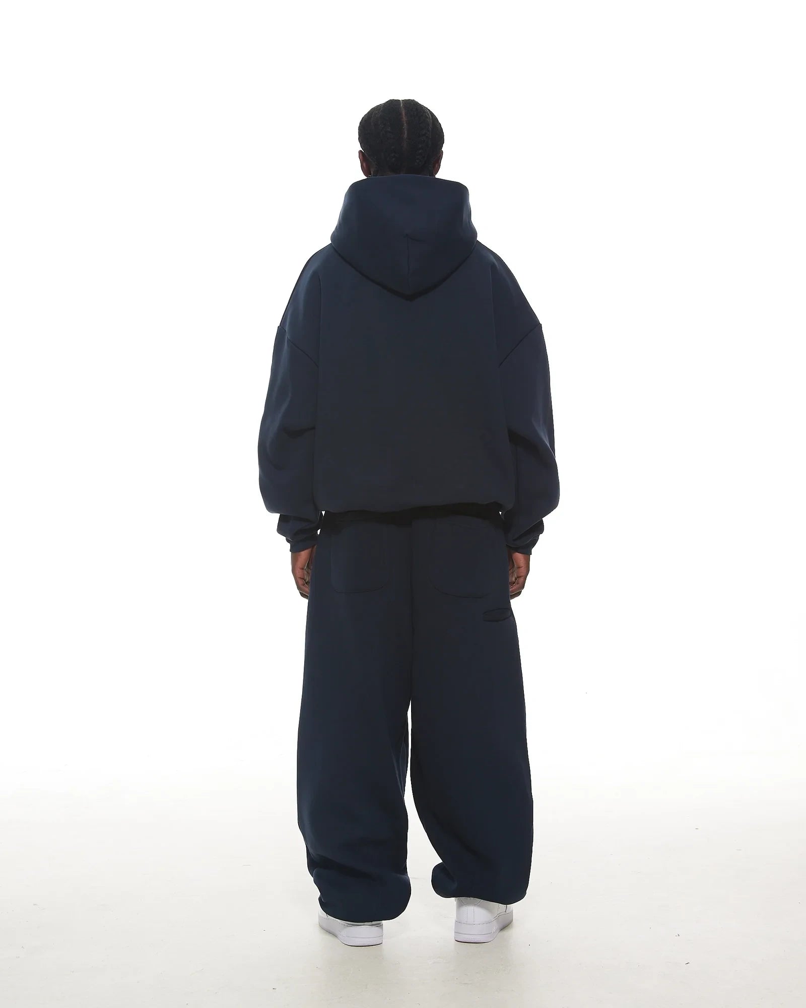 Person wearing a navy tracksuit on a white background