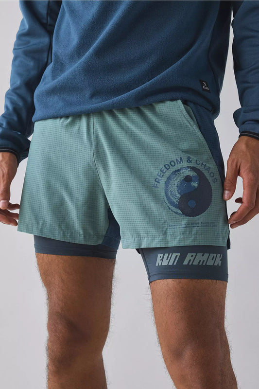 Person wearing teal running shorts with a logo and text on a plain background