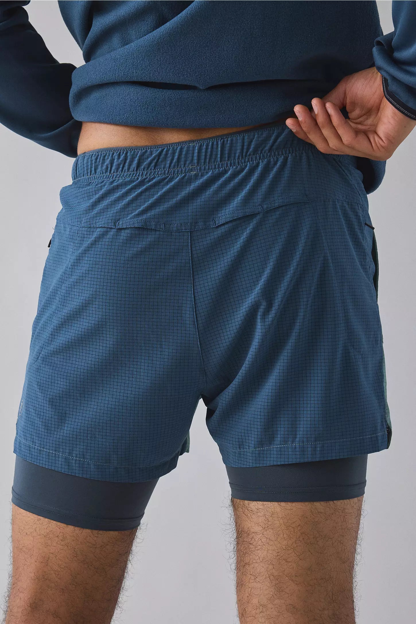 Person wearing blue athletic shorts on a plain background