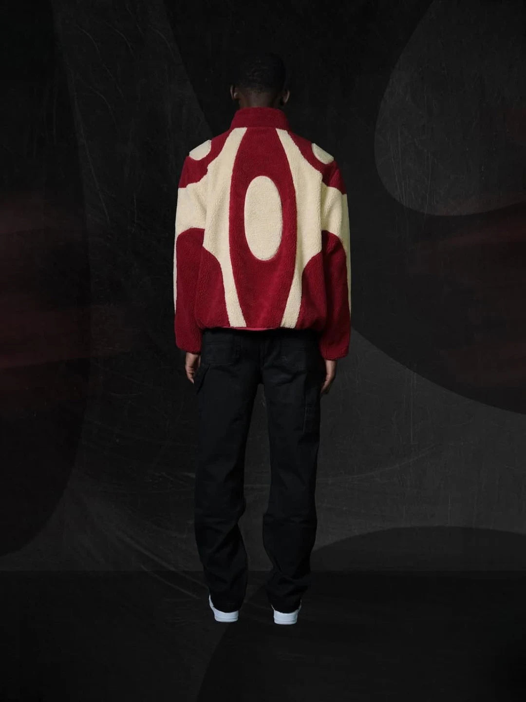 Person wearing a red and white patterned jacket in a dark setting