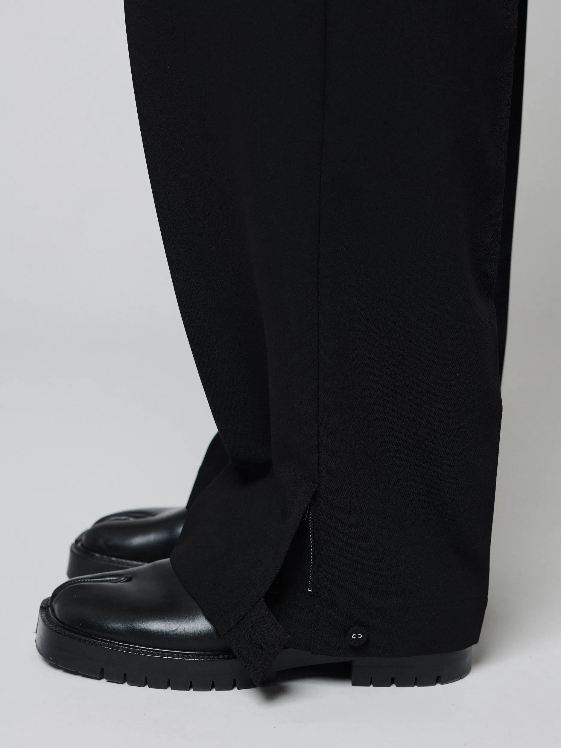 Black Pants with Double front pleats and adjustable side tabs offer a comfortable, customizable fit, while functional pockets and zip-open hem slits add versatility. Crafted from a smooth cotton blend, they are ideal for refined casual, elevated streetwear, and polished off-duty styling.