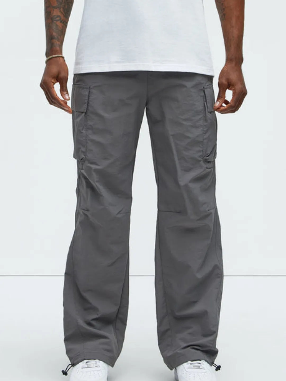 Person wearing gray cargo pants with pockets on a white background