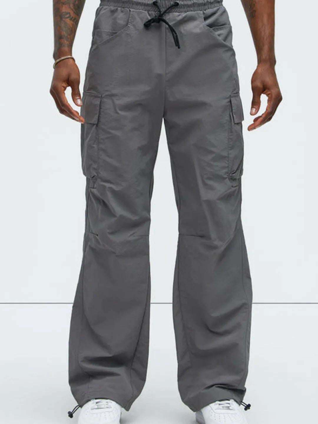 Person wearing gray cargo pants with pockets on a white background