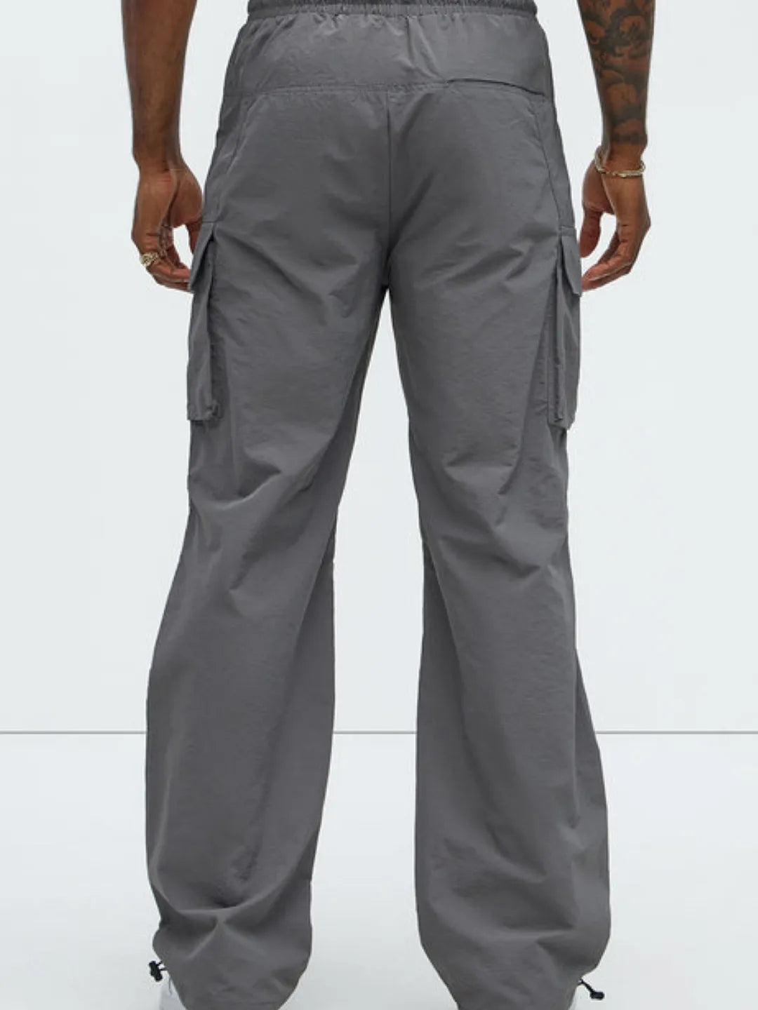 Person wearing gray cargo pants with pockets on a white background