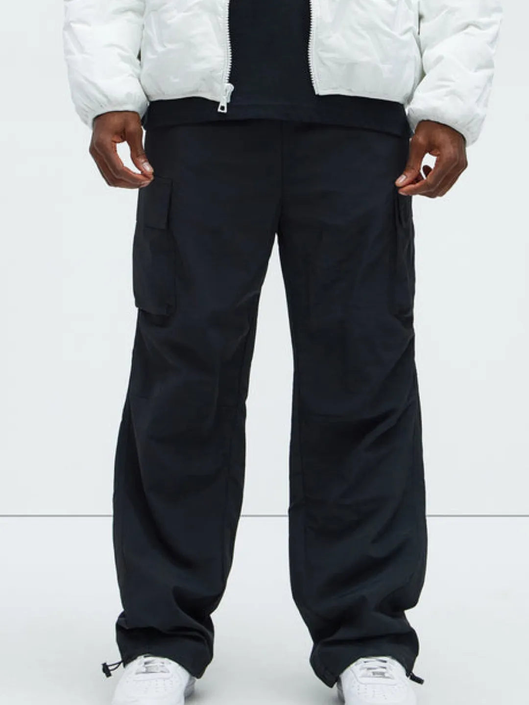 Person wearing black cargo pants with pockets on a white background