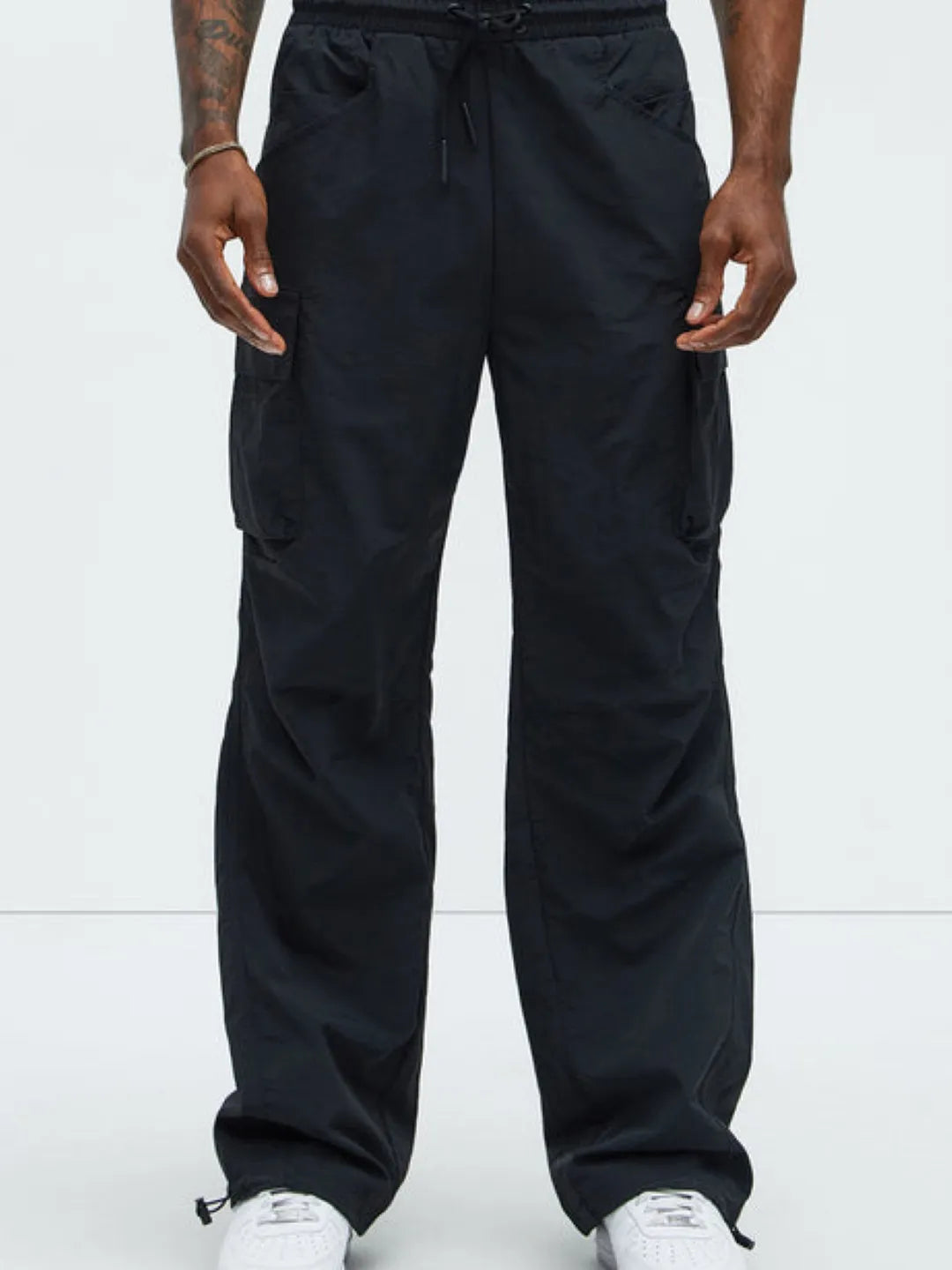 Person wearing black cargo pants with pockets on a white background