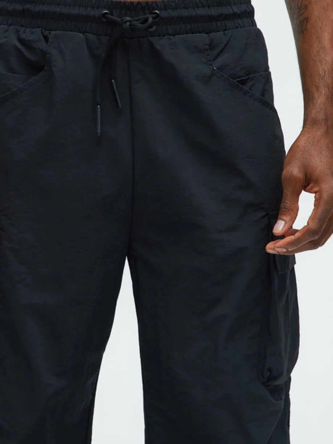 Person wearing black cargo pants with pockets on a white background