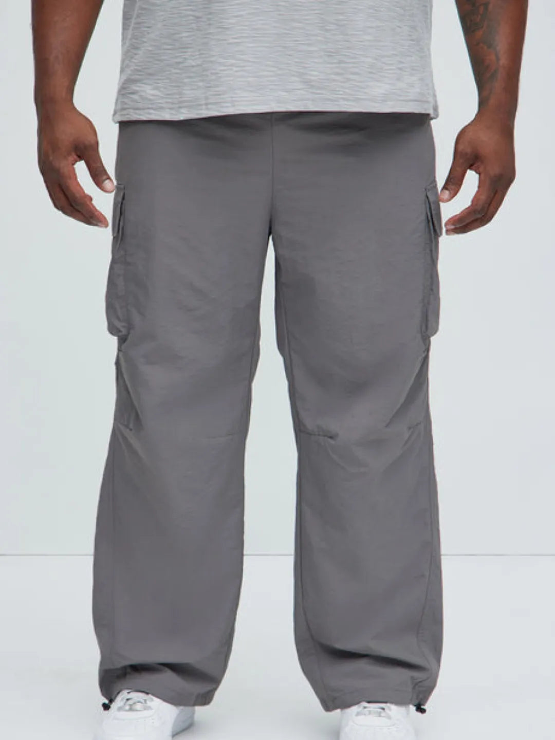 Person wearing gray cargo pants with pockets on a white background