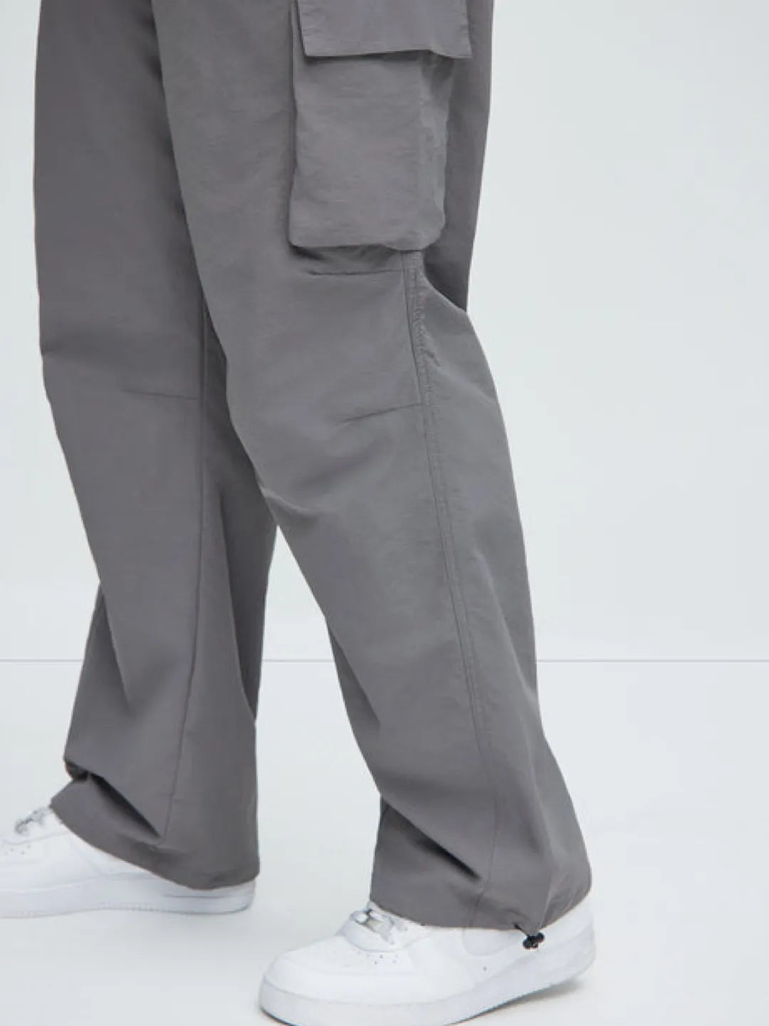 Person wearing gray cargo pants with pockets on a white background