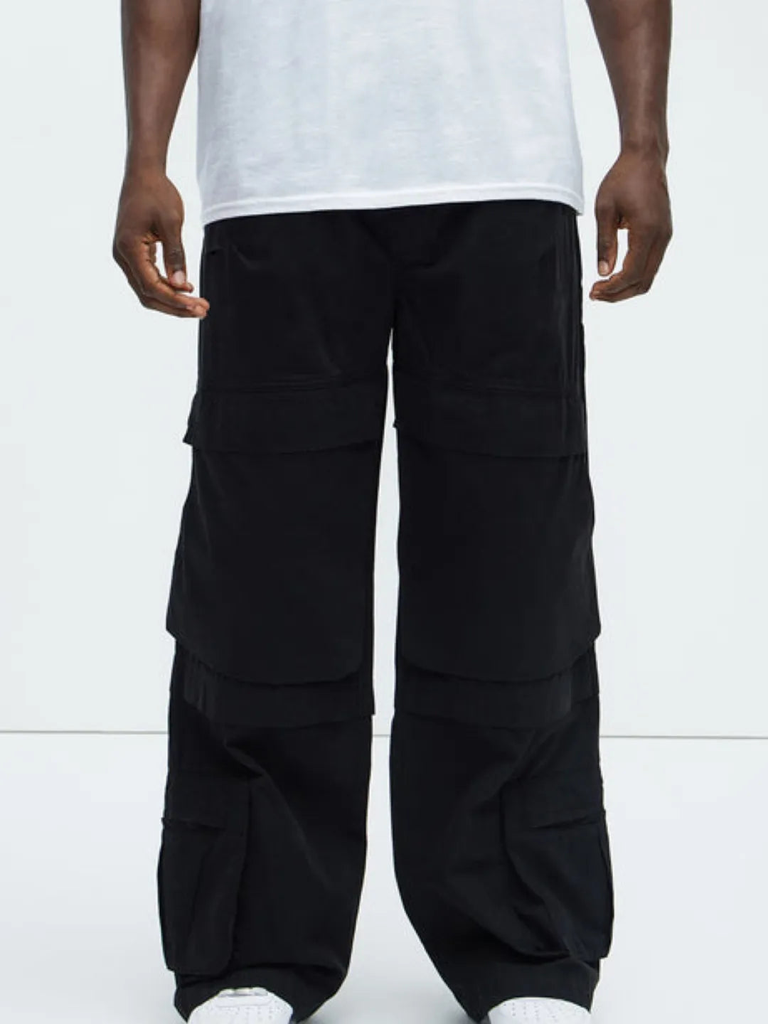 Person wearing a white t-shirt and black  cargo pants on a white background