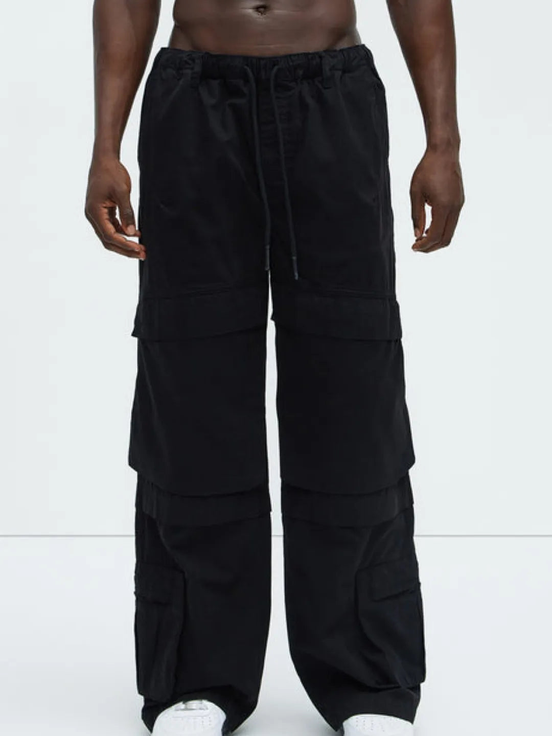 Person wearing a white t-shirt and black  cargo pants on a white background