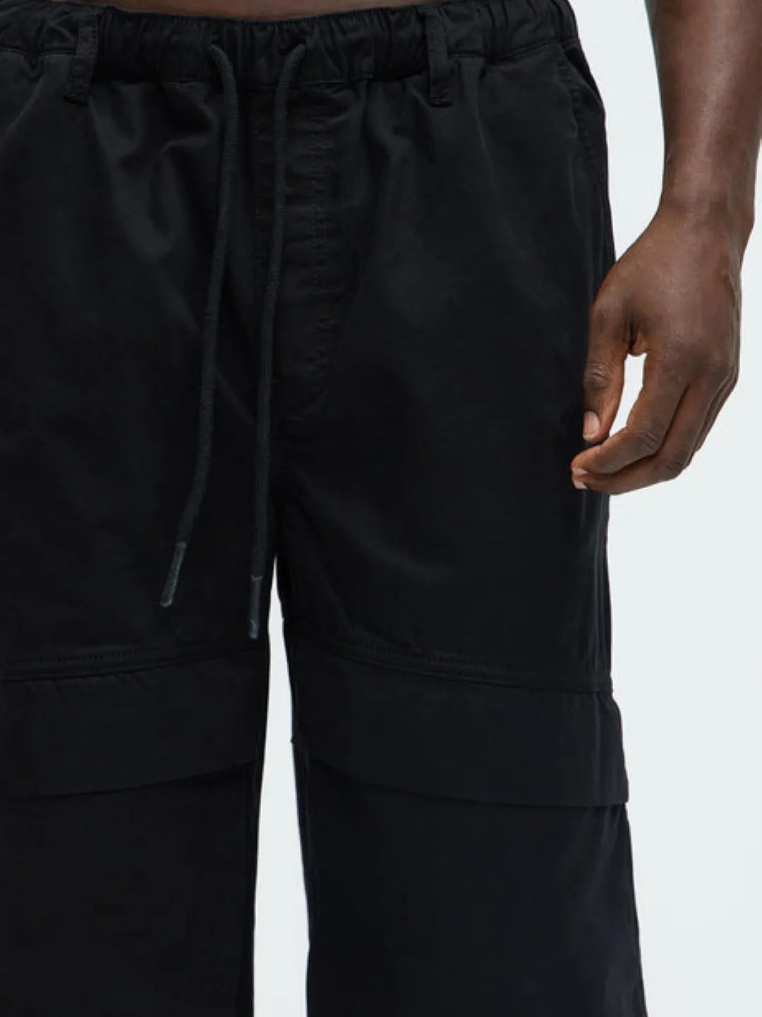 Person wearing a white t-shirt and black  cargo pants on a white background