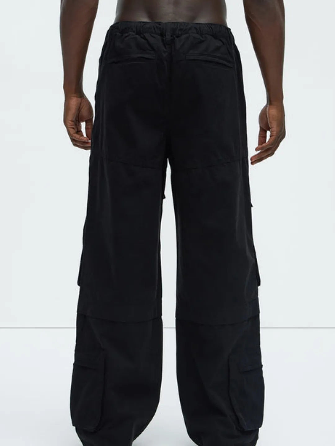 Person wearing a white t-shirt and black  cargo pants on a white background