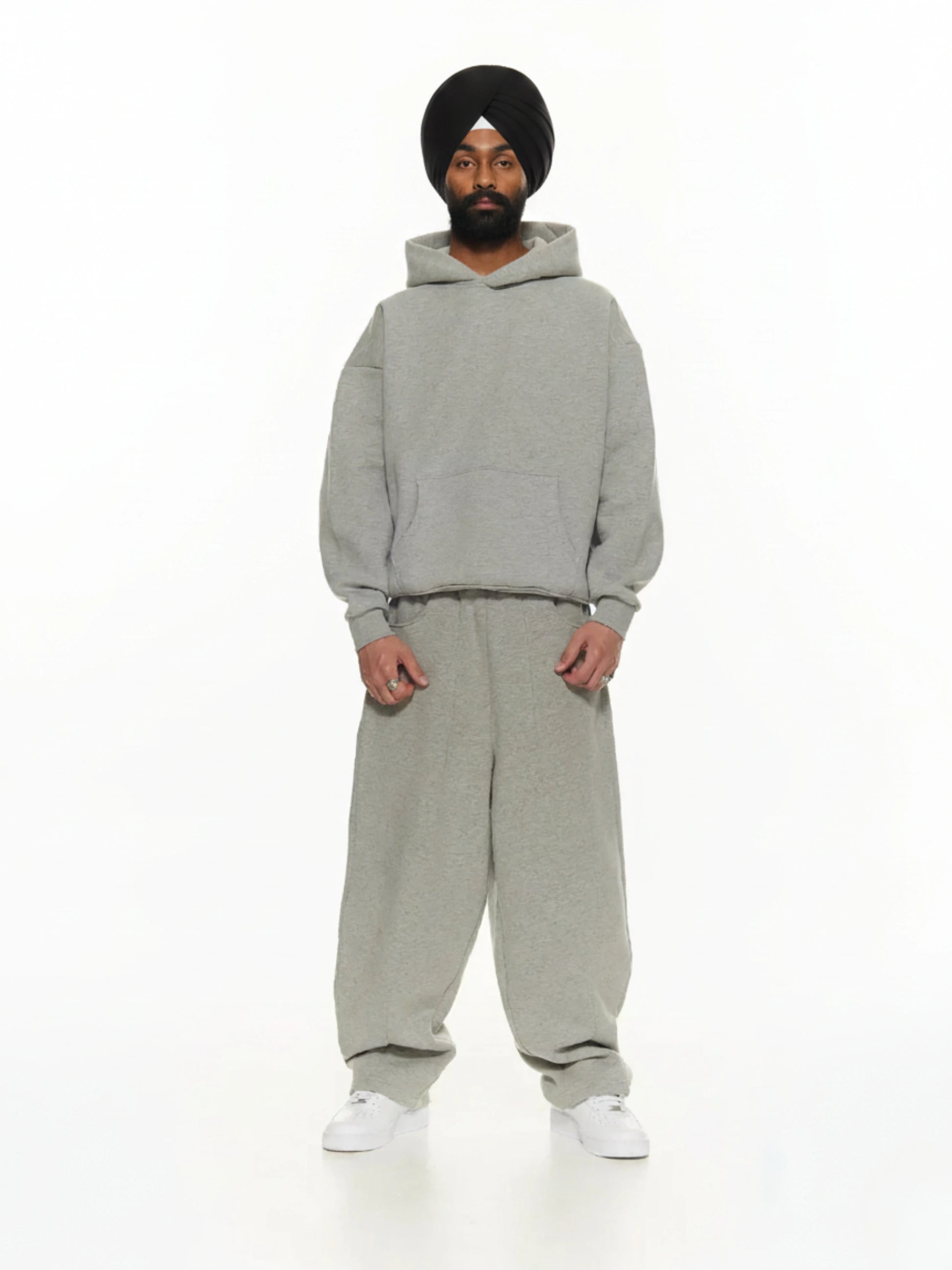 Person wearing a gray hoodie and pants set on a white background
