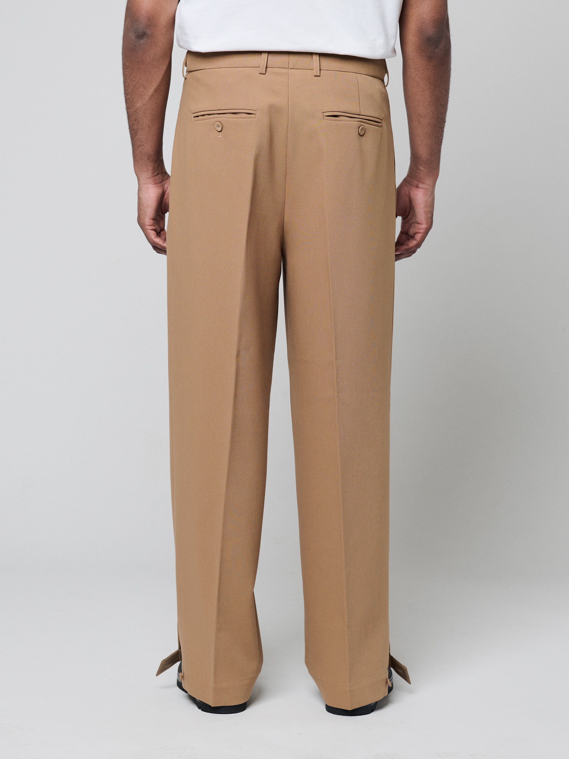 Tan Pants with Double front pleats and adjustable side tabs offer a comfortable, customizable fit, while functional pockets and zip-open hem slits add versatility. Crafted from a smooth cotton blend, they are ideal for refined casual, elevated streetwear, and polished off-duty styling.