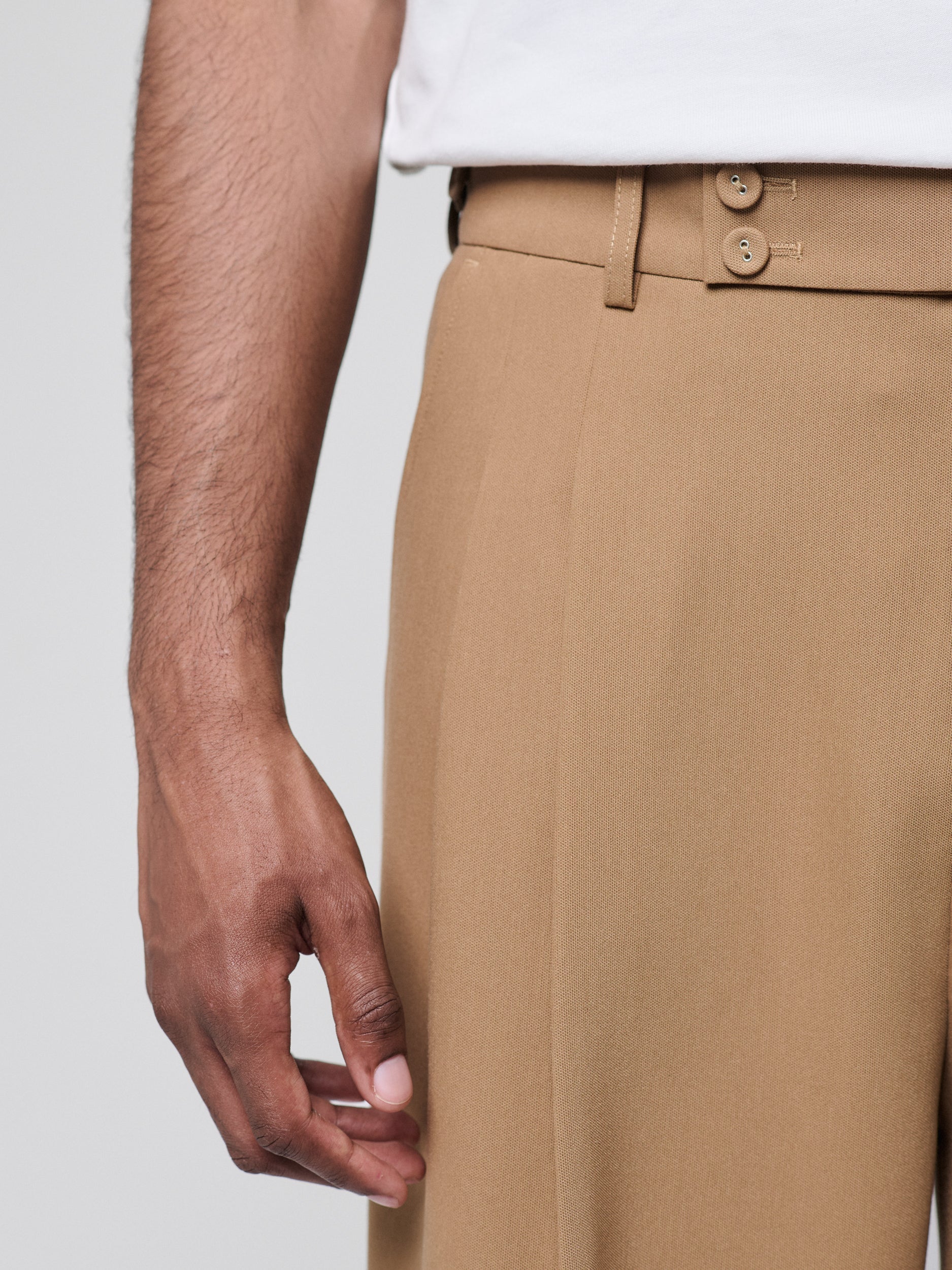 Tan Pants with Double front pleats and adjustable side tabs offer a comfortable, customizable fit, while functional pockets and zip-open hem slits add versatility. Crafted from a smooth cotton blend, they are ideal for refined casual, elevated streetwear, and polished off-duty styling.