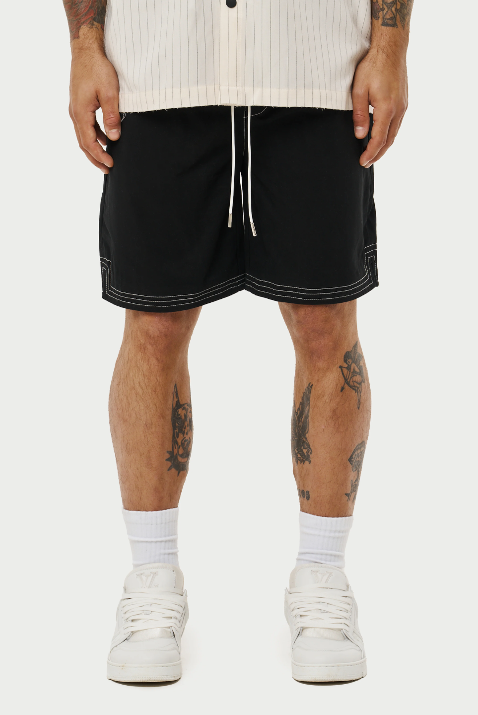 This image displays a model wearing a pair of contrast stitch woven shorts, perfect for a relaxed yet stylish look. The shorts are black with a distinctive white contrast stitching that accentuates the seams and pockets, adding a modern touch to the classic design.