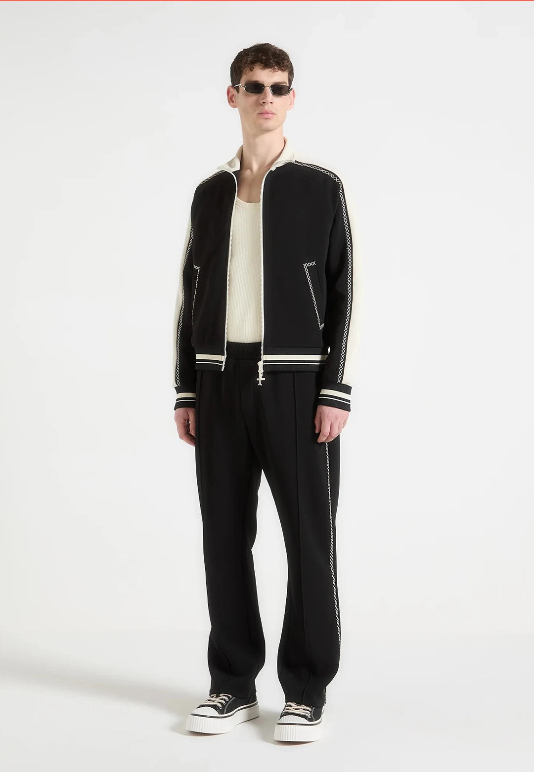Man wearing a black tracksuit with white stripes on a white background